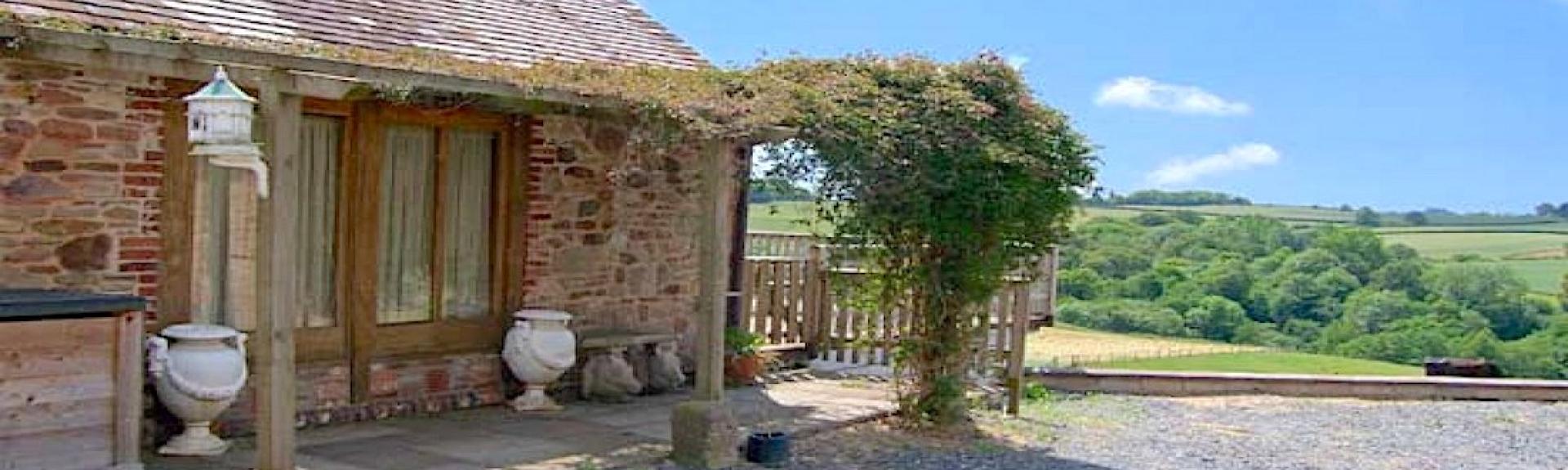 Cloistered extrior of a single-storey barn conversion with a creeper-covered pergola.