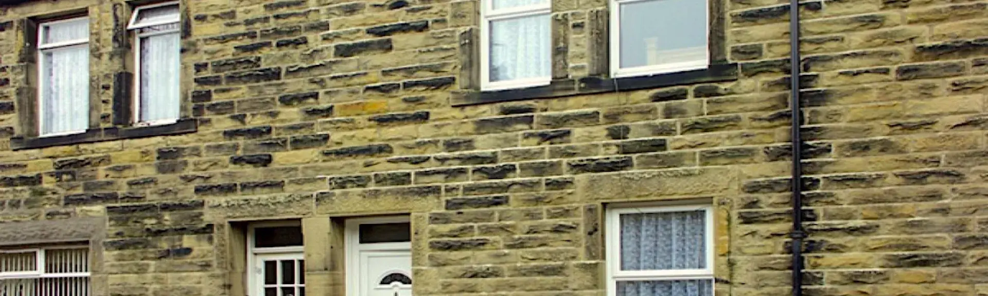 Stone-built terraced cottage with a flower-filled window basket.