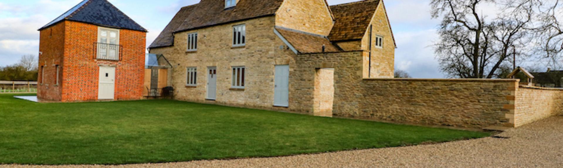 Exterior of a large stone-built, 3-storey Oxfordshire farmhouse and garden.