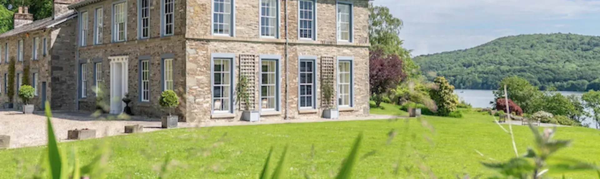 Exterior  of a country house in the Lake District with a lake in the background.