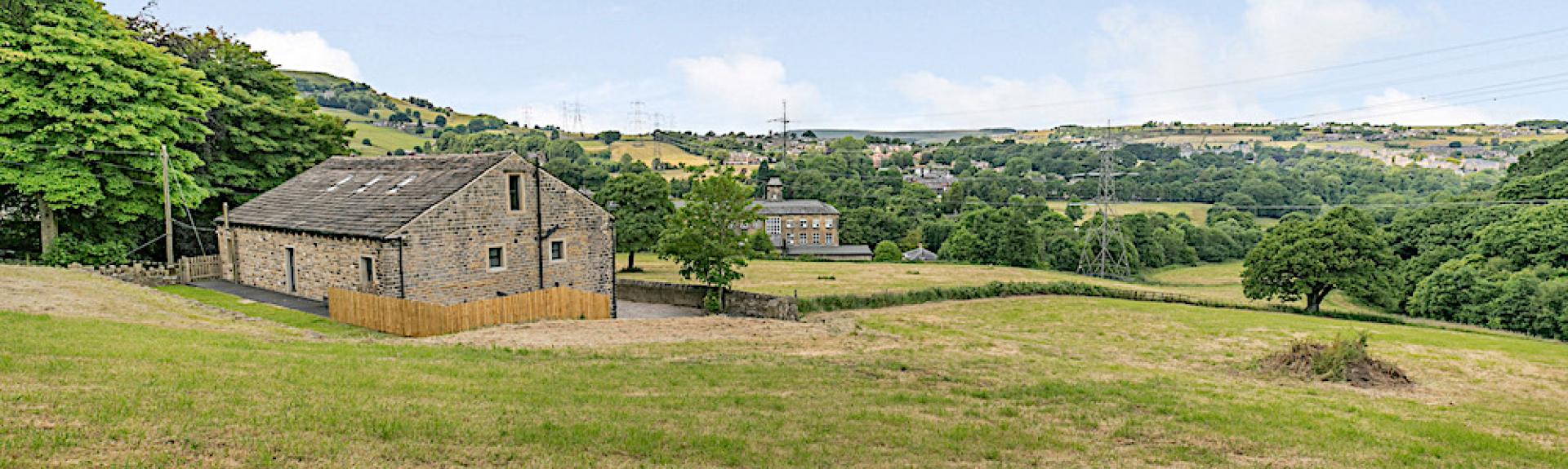Remote barn conversion surrounded by open fields and mature trees in The Pennines.