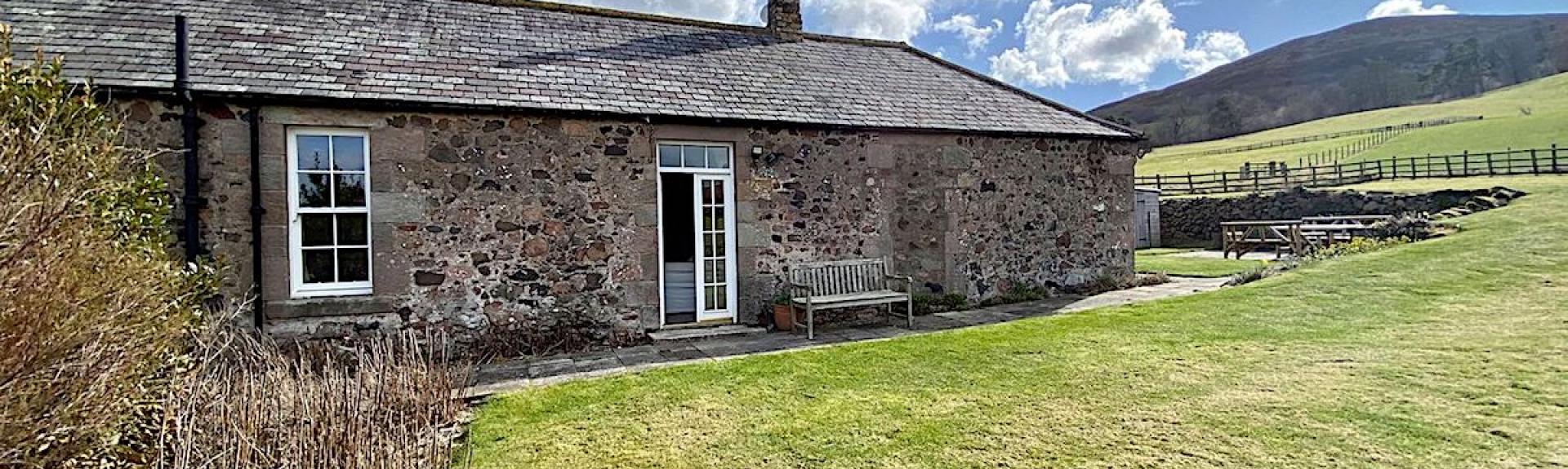 Large lawns surround a ground-floor barn conversion in remote, open Northumberland countryside