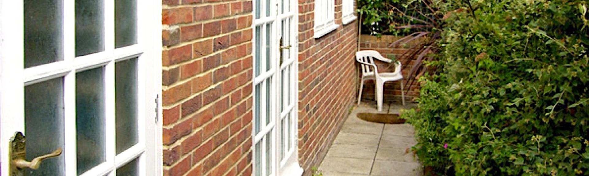 A paved path leads to the side entrance of a brick built, Isle-of-Wight holiday cottage 