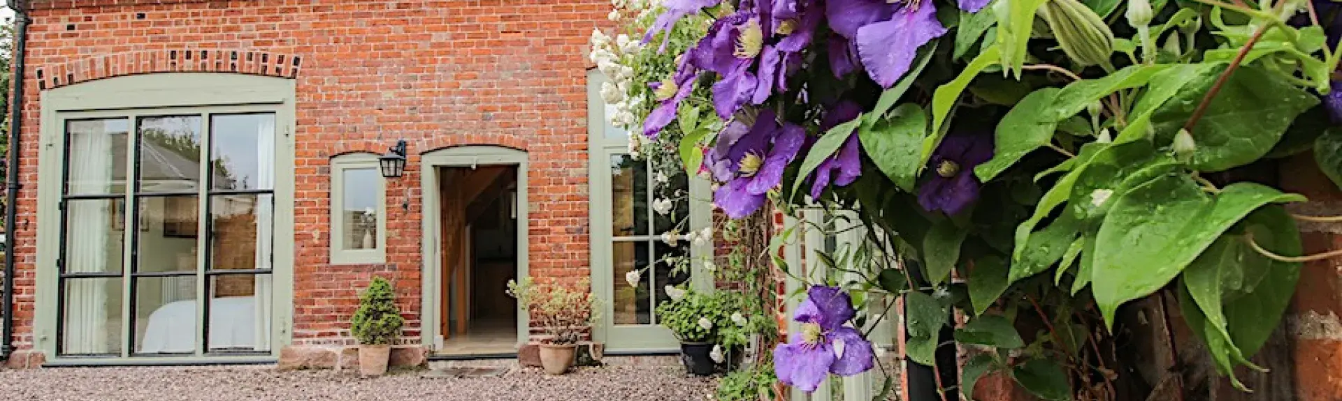 A flowering vine cimbs the walls of aconvrted coach house overlooking a courtyard in Shropshire