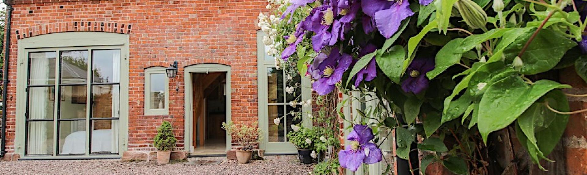 A flowering vine cimbs the walls of aconvrted coach house overlooking a courtyard in Shropshire