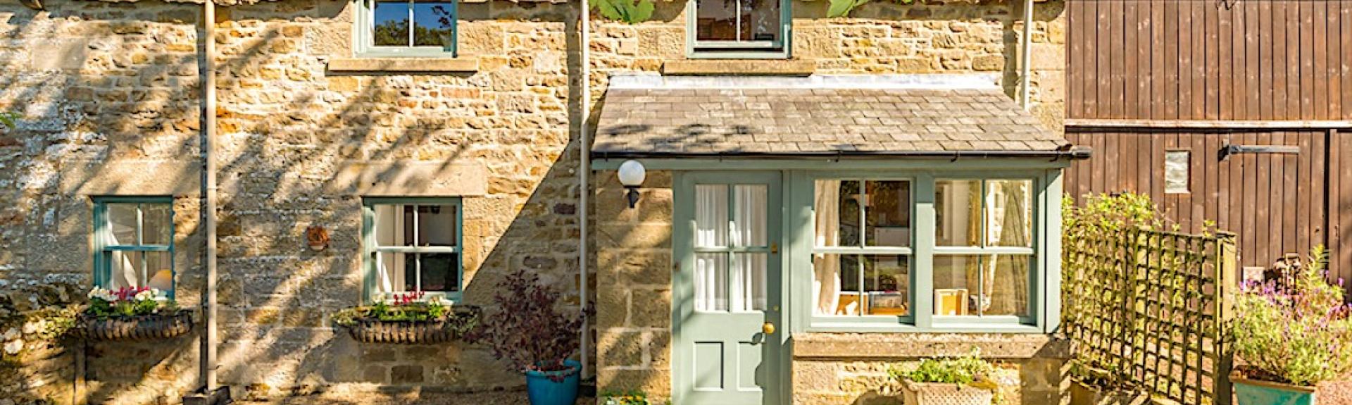 Exterior and front garden of a 2-storey stone-built Northumberland holidy cottage.