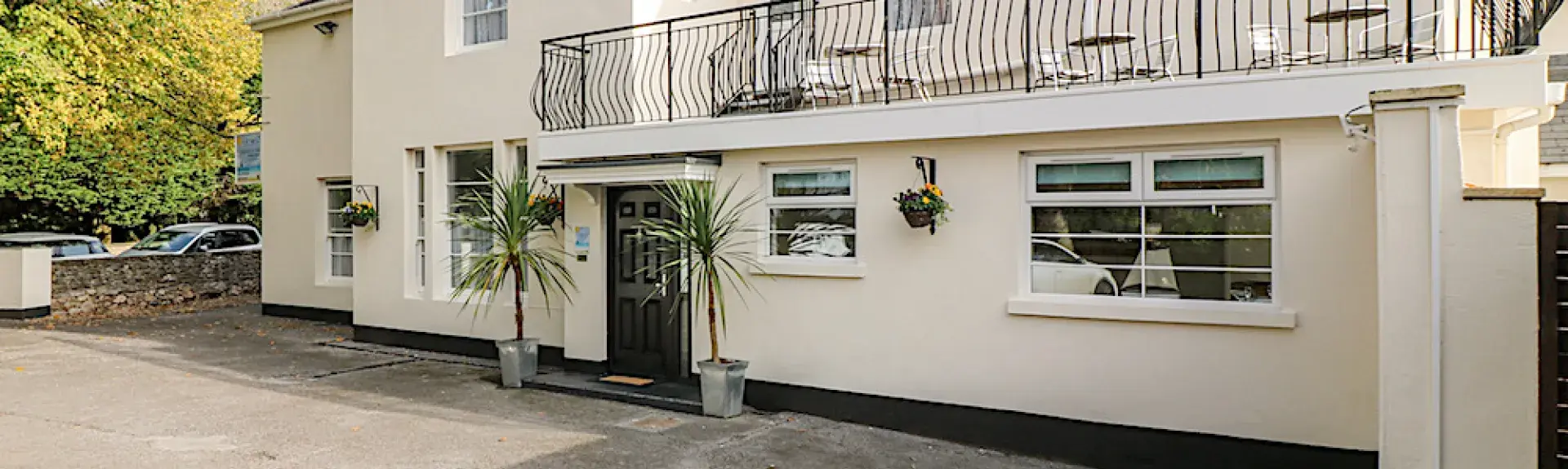 Exterior of a large Victorian house in Torquay with a long balcony overlooks a courtyard.