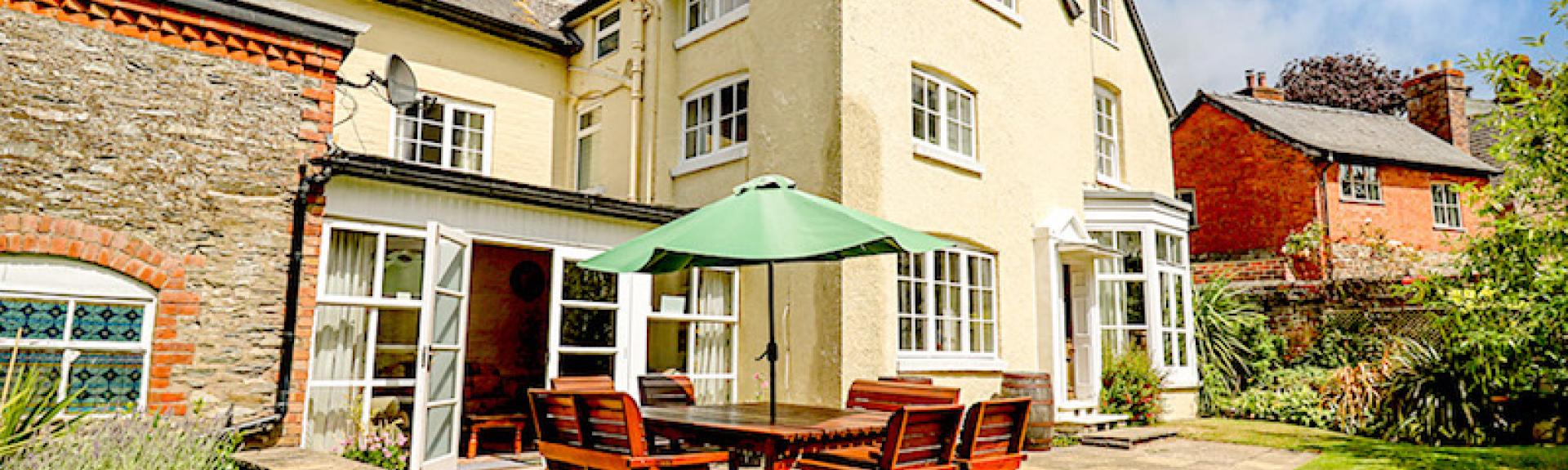 3 storey exterior of a large modern Shropshire holiday home with outdoor dining facilities and a large laen.