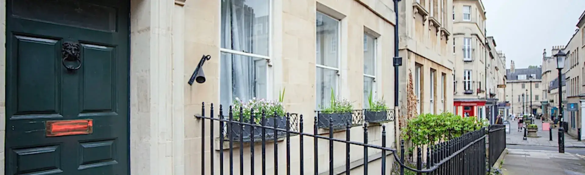 A 4-storey, classic Bath-stone terraced house overlooking a street.