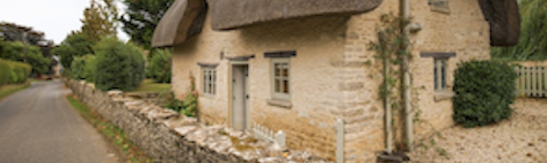 Exterior of a thatched 2-storey village holiday cottage in the Cotswolds.