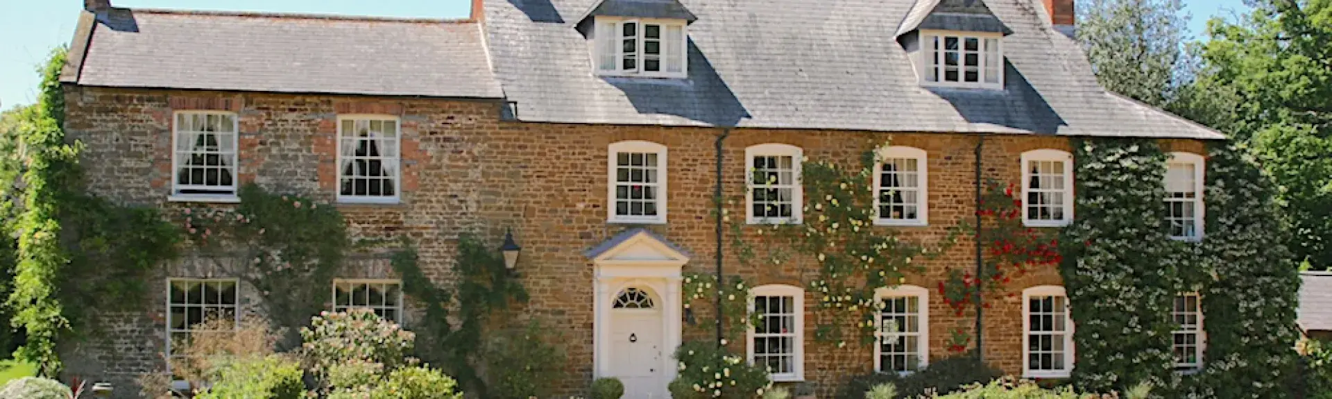 A large old Northamptonshire rectory looks out over flowerbeds and a spacious lawn.