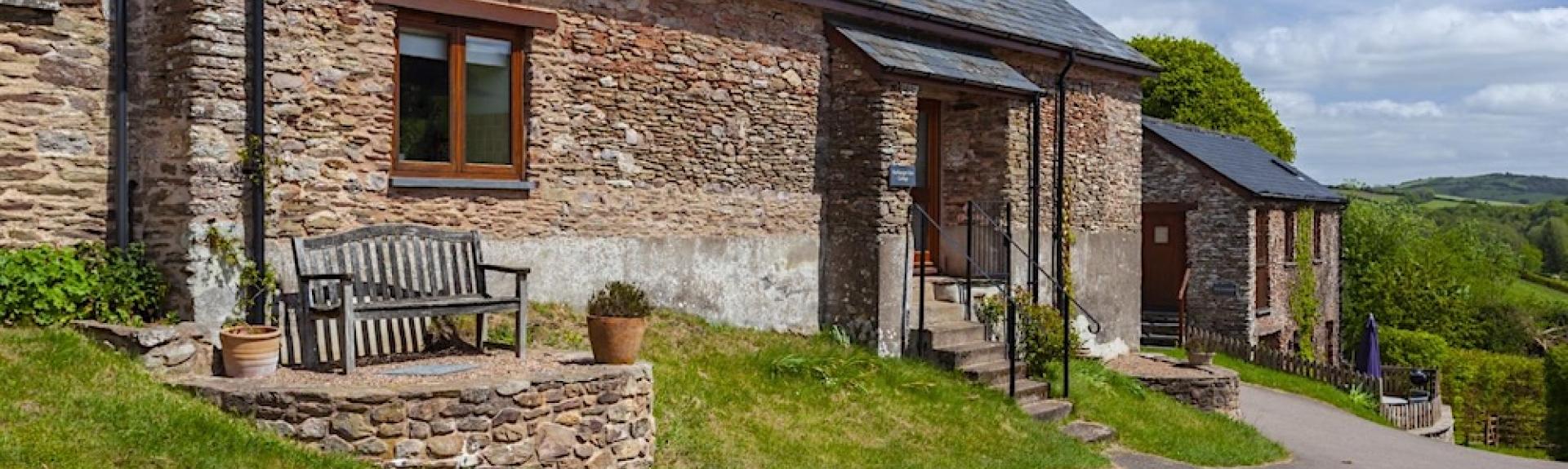 An Exmoor stone barn conversion overlooks a bend in a country lane. 