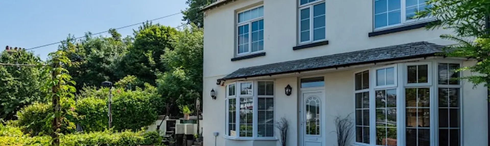A 2-storey exterior of a Looe holiday let with bay windows and large garden.