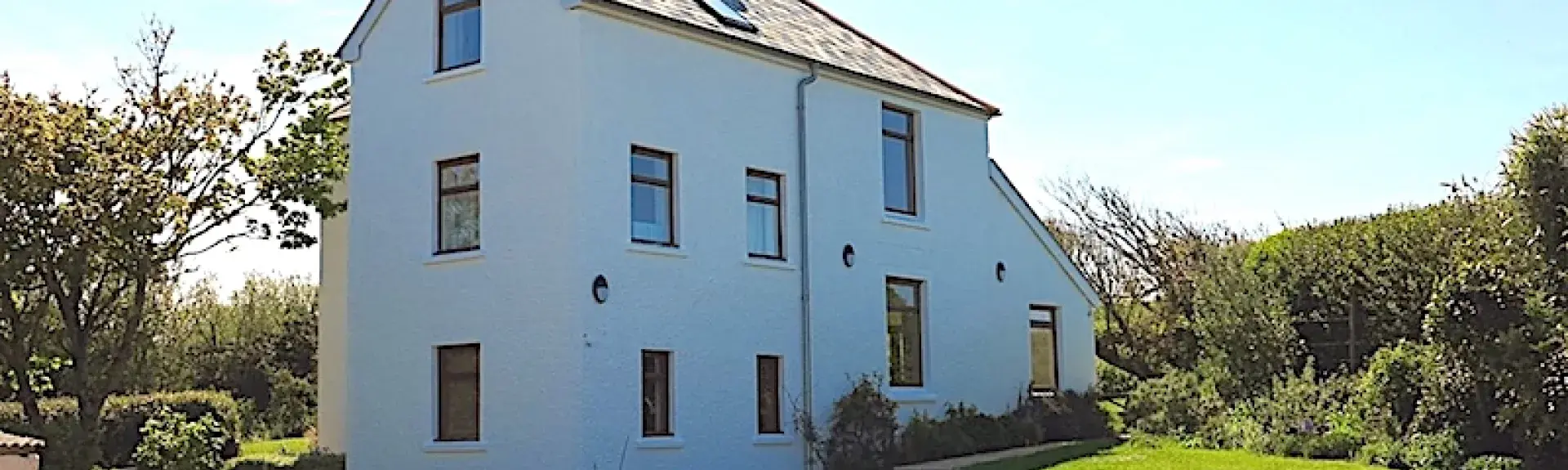 A 3-storey holiday home is surrounded by lawns and a spacious block paved parking area.