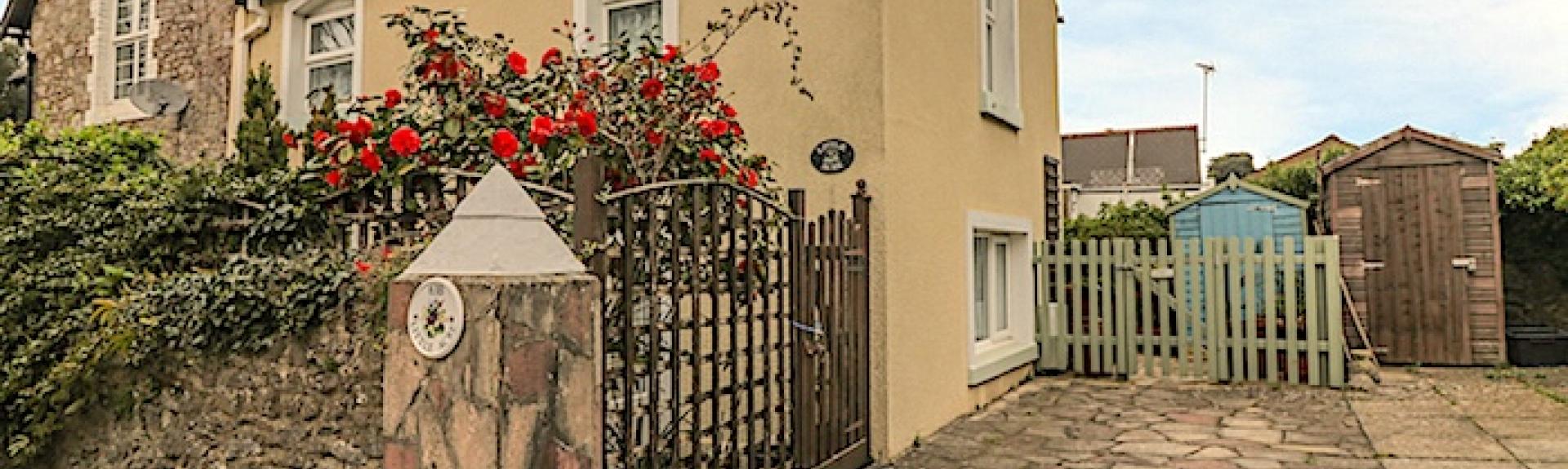 A Torquay holiday cottage sits behind a rose covered stone wall.