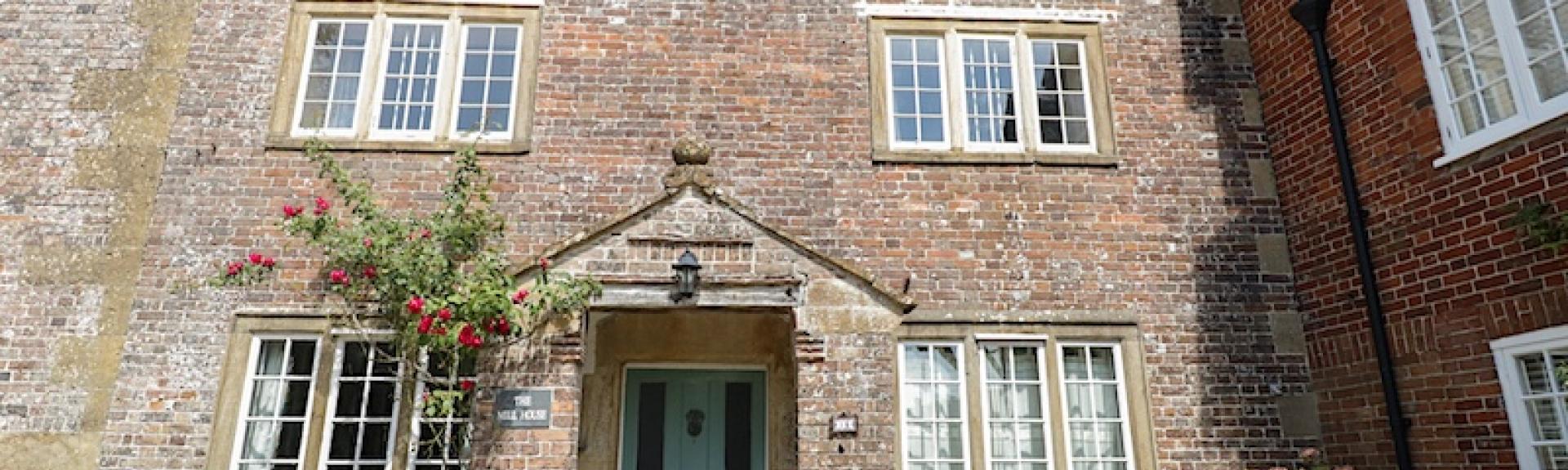 A 3-storey, brick-built, Dorset Mill House overlooks a cobbled courtyard.