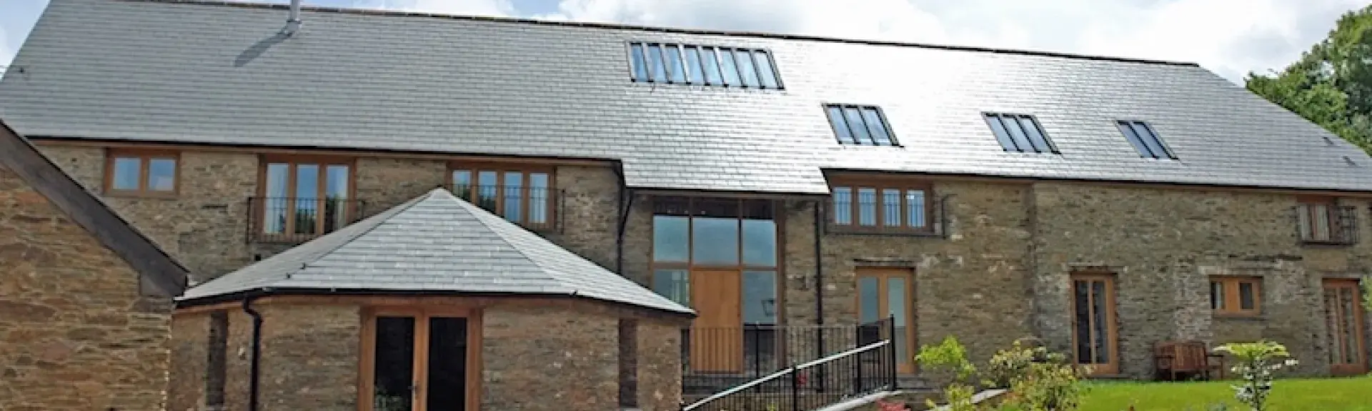 Exterior of a large 2-storey barn conversion surrounded by lawns.