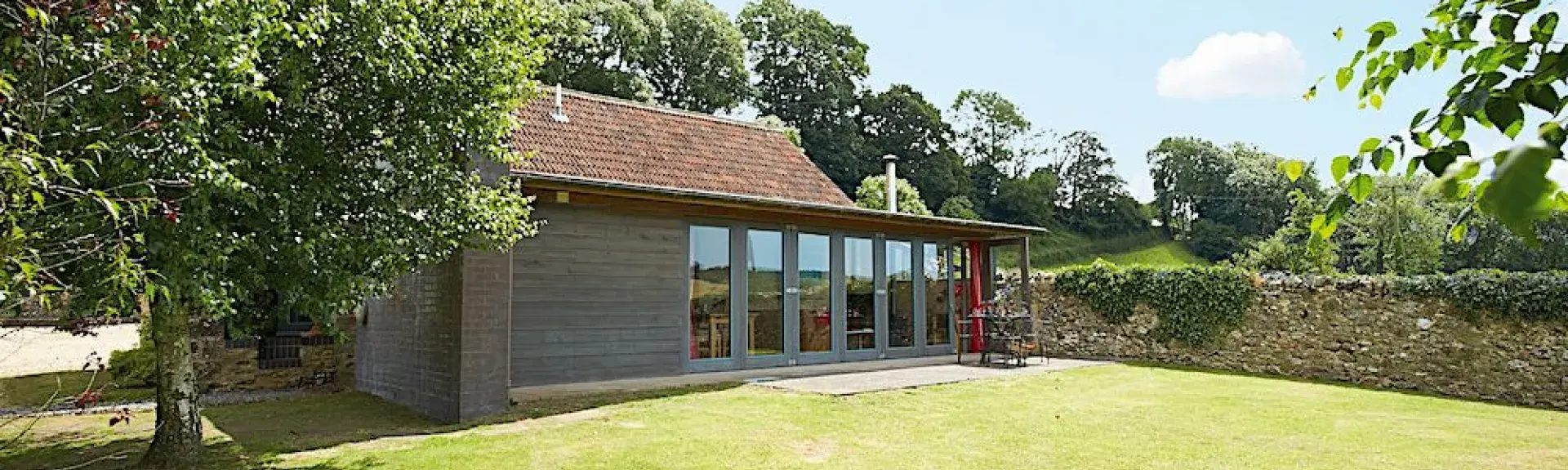 A contemporary wooden holiday lodge in Est Devon overlooking a large walled lawn.