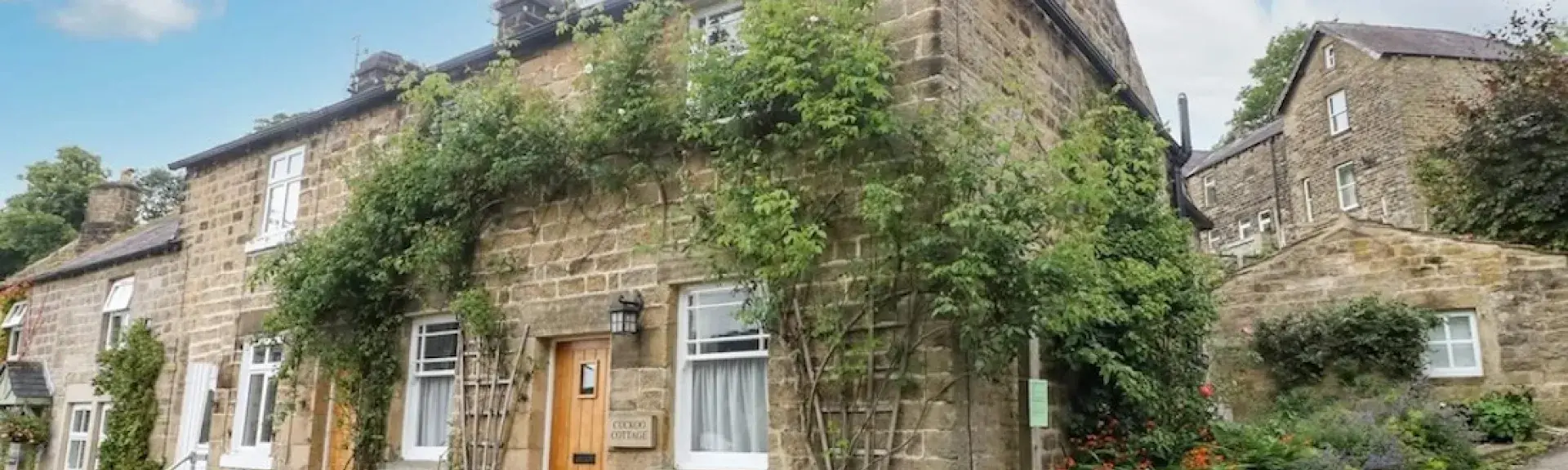 A vine-clad, stone-built, corner cottage on an empty village street.