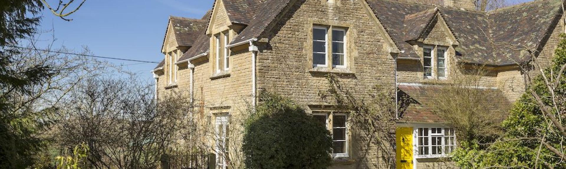 Exterior of a vine-clad Cotswold honeystone cottage in Chipping Norton.