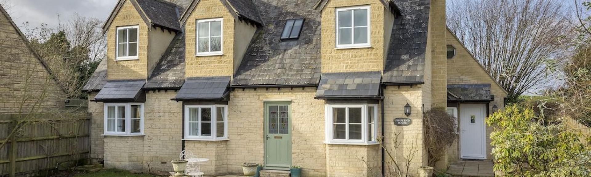 Exterior or a modern Cotswold honeystone house with triple bay windows