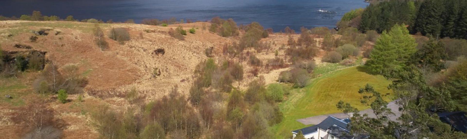 Aerial photo of a Loch in the Scottish Highlands with a holiday cottage in the foreground.