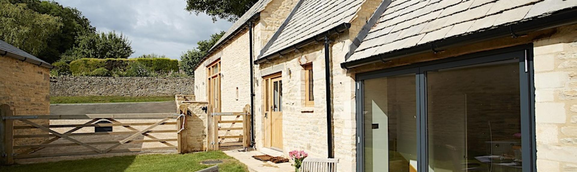 A side elevation of a Cotswold Barn conversion with wide full-height sliding French Windows.