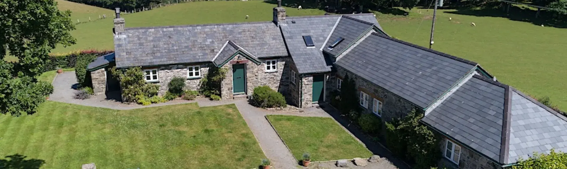 L-shaped exterior of a barn conversion surrounded by open fields.