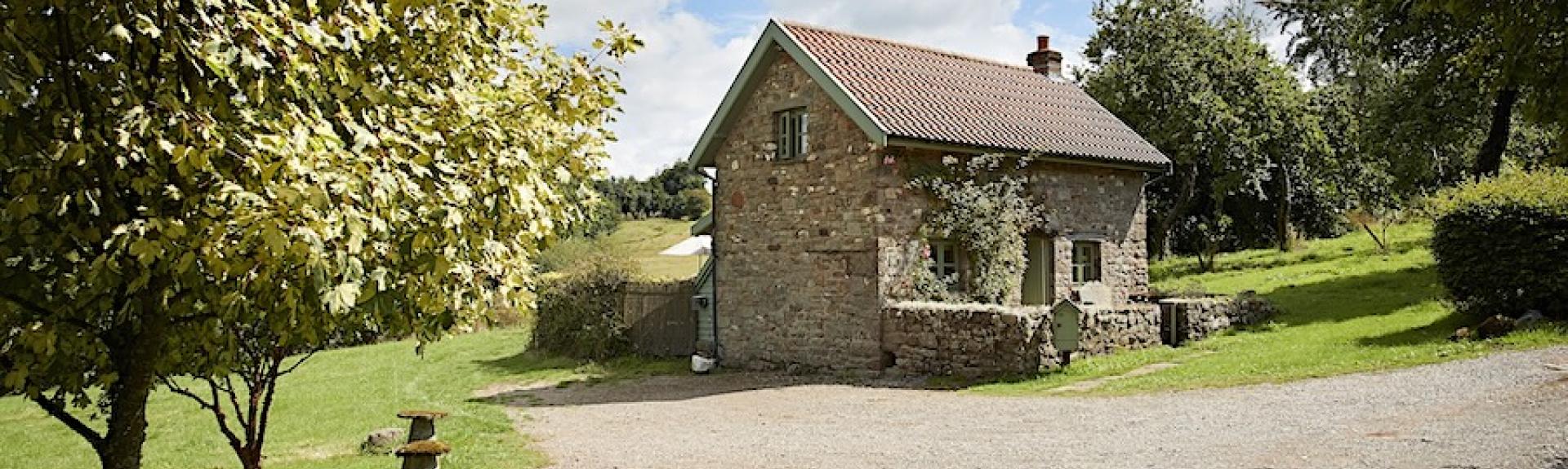 A stone drive leads to a barn conversion surrounded by well-mown lawns.