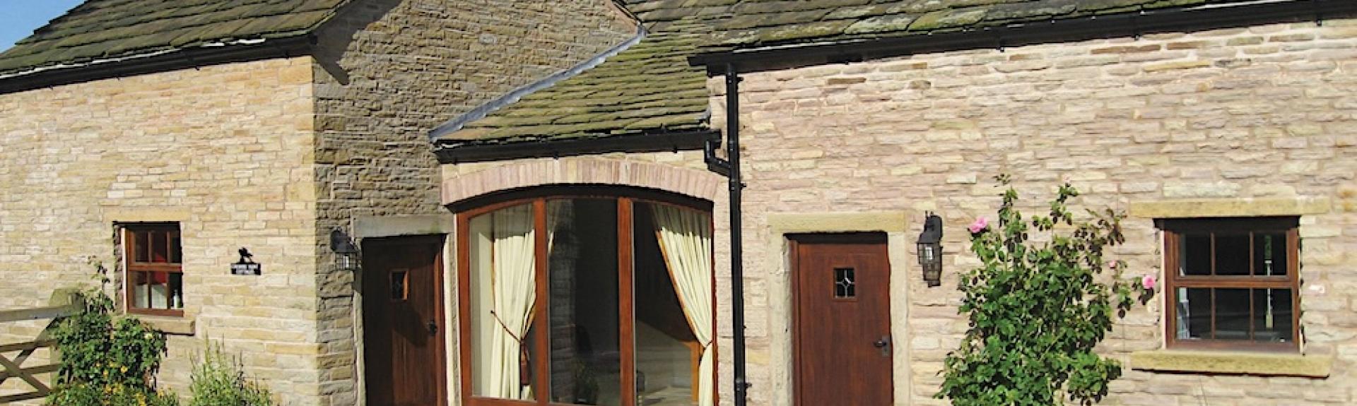 Exterior of a single-storey, stone-built, Cheshire holiday cottage.