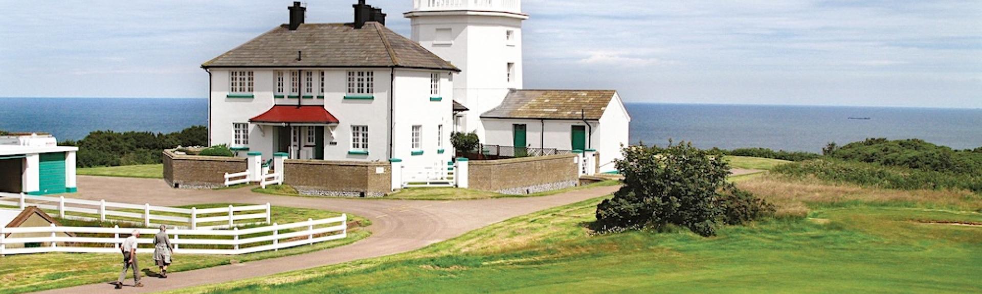 A lighthouse on the edge of a golf links with sea views in the background.