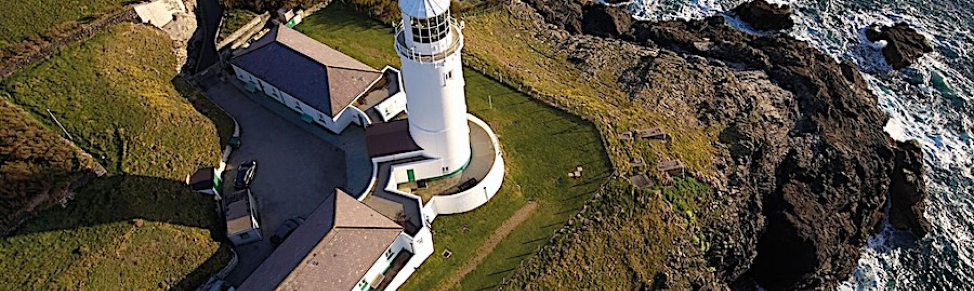 Aerial view of a Cornish Lighthouse complex overlooking the sea.