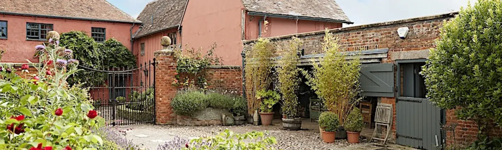 Exterior of a small Gloucestershire cottage and adjoining stable in a garden.