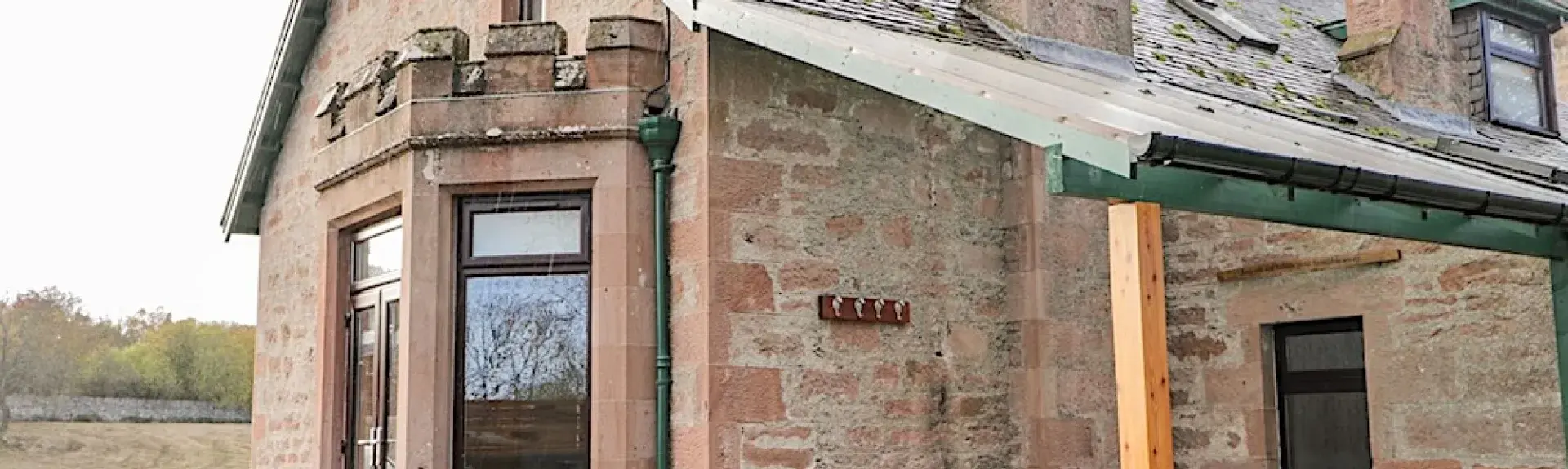 Exterior of a stone-built Highland holiday cottage with a hot-tub on its deck.