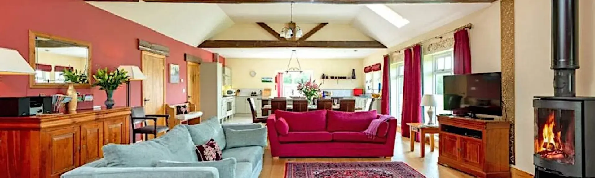 A large open plan lounge with beamed ceiling, widescreen TV and comfy sofas.