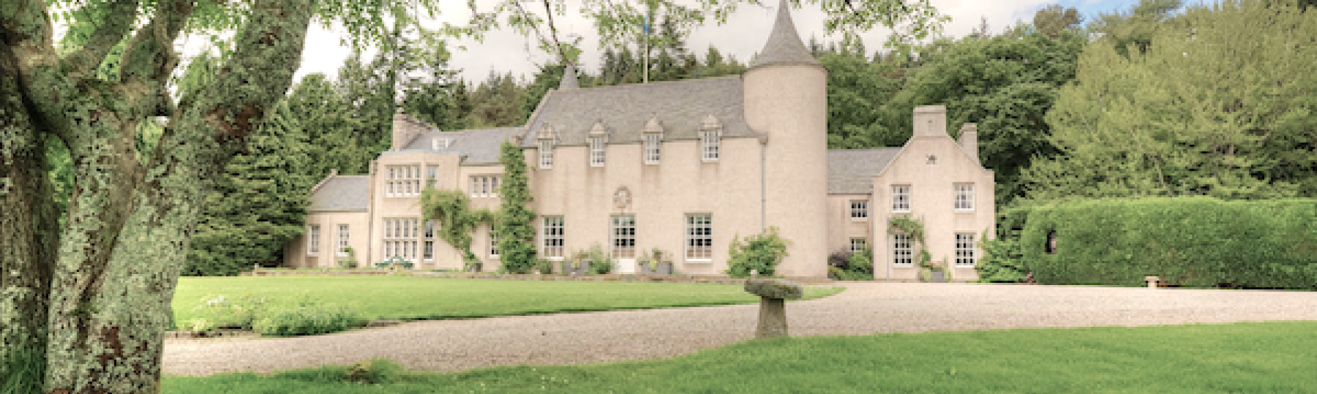 A Highland Country House surrounded by wooded parkland.
