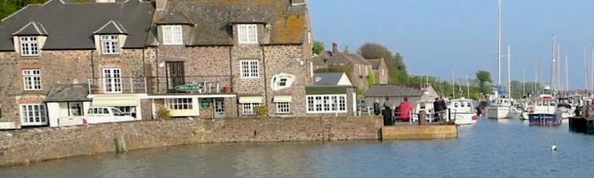 Exterior of a old holiday cottage overlooking Porlock Weir harbour at high tide.