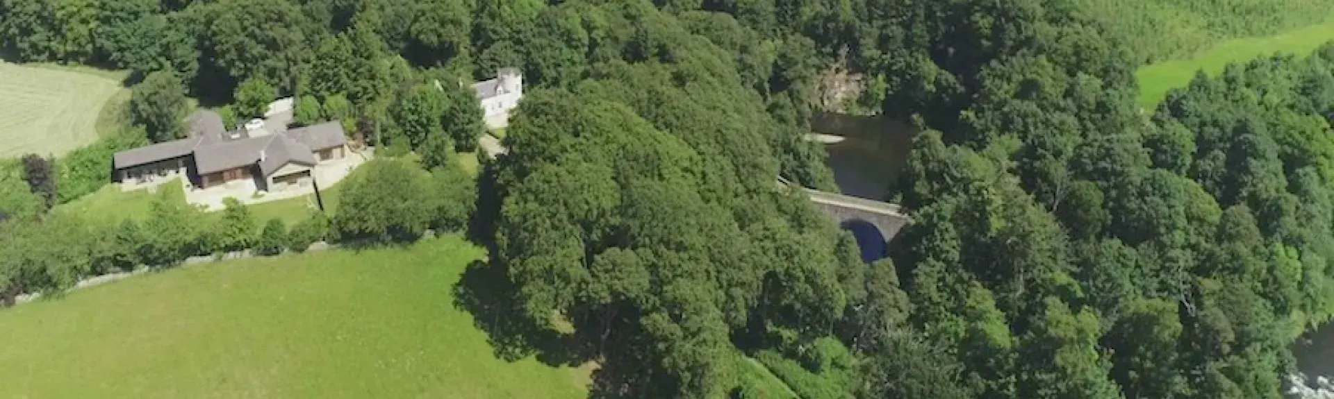 Aerial view of cottages overlooking a river and surrounded by trees.