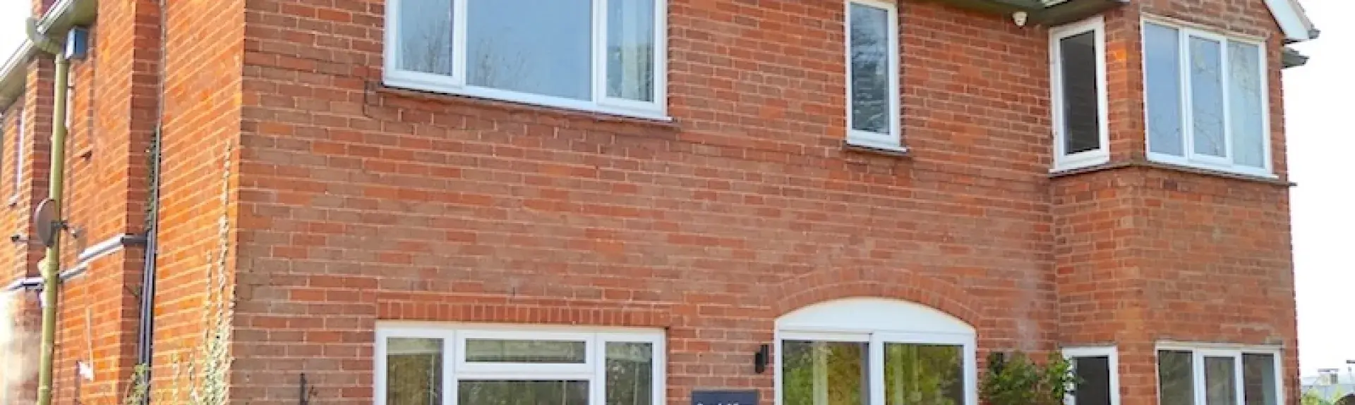 Double-fronted exterior of a rural holiday cottage with a large paved terrace.