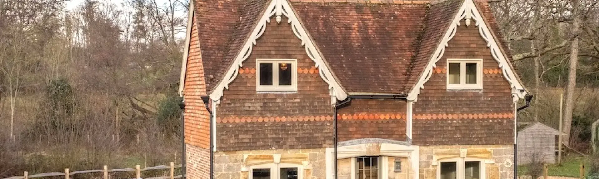 Twin-gabled extertior of a Kent farmhouse surrounded by a large, fenced lawn