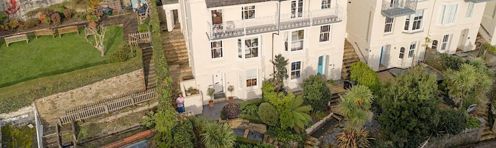 A semi-detached, 4-storey holiday home with a full-width shaded balcony overlooks the waterside.