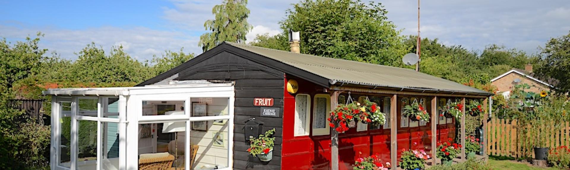 Eterior of a vintage railway carriage converted to a holiday rental in a garden.