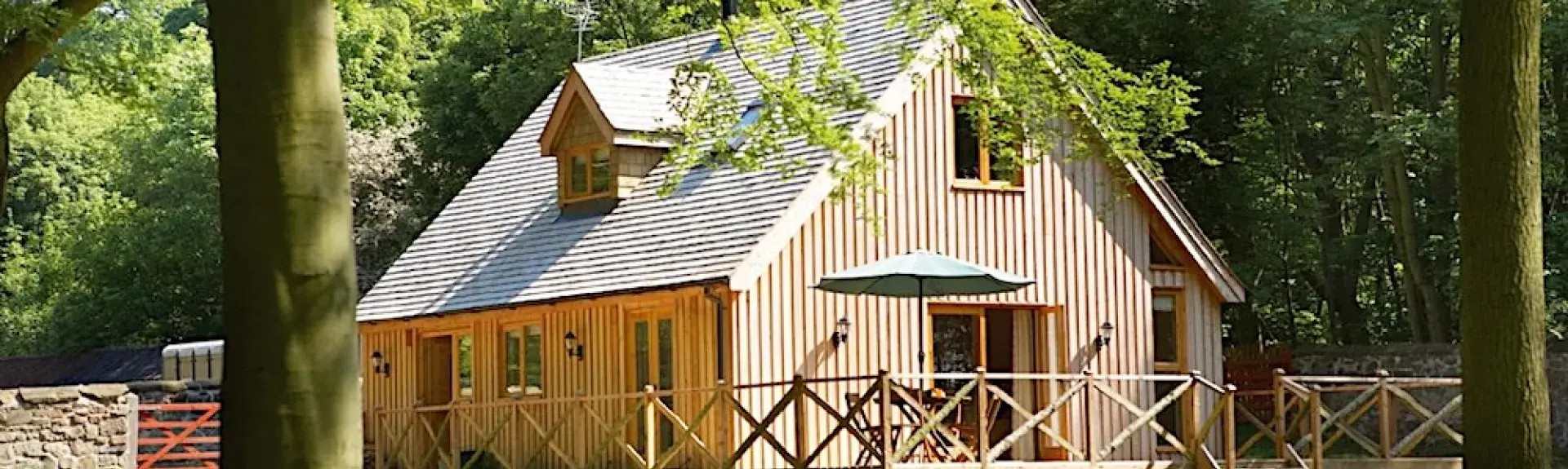 A 2-storey, timber-walled lodge in a woodland glade.