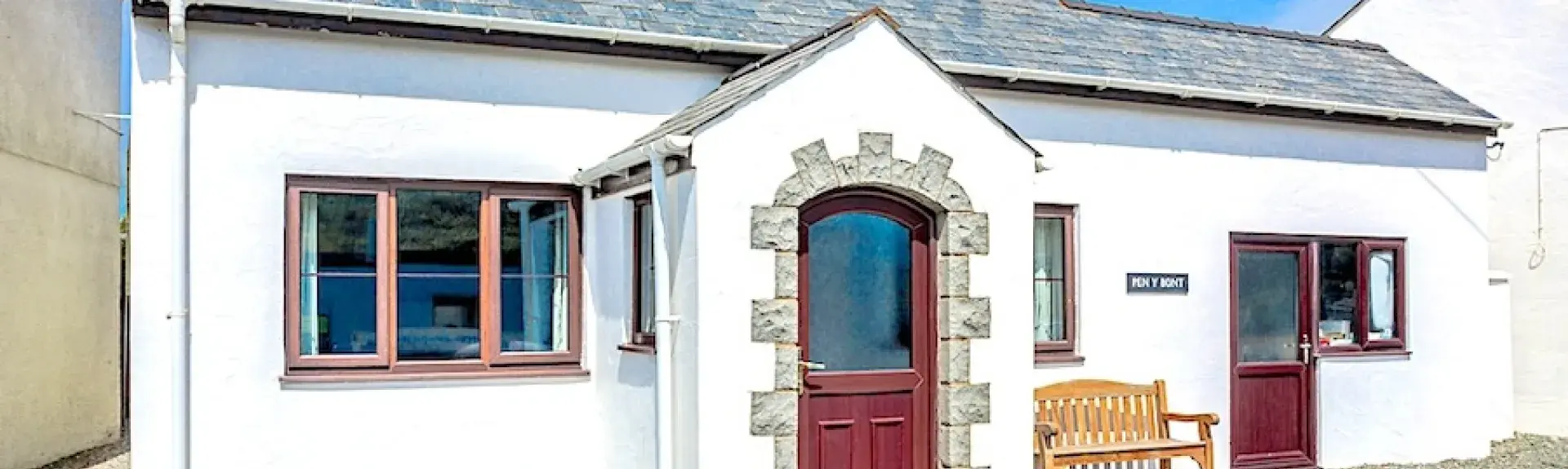 Exterior of a double-fronted cottage with a covered porch on a sunny day.