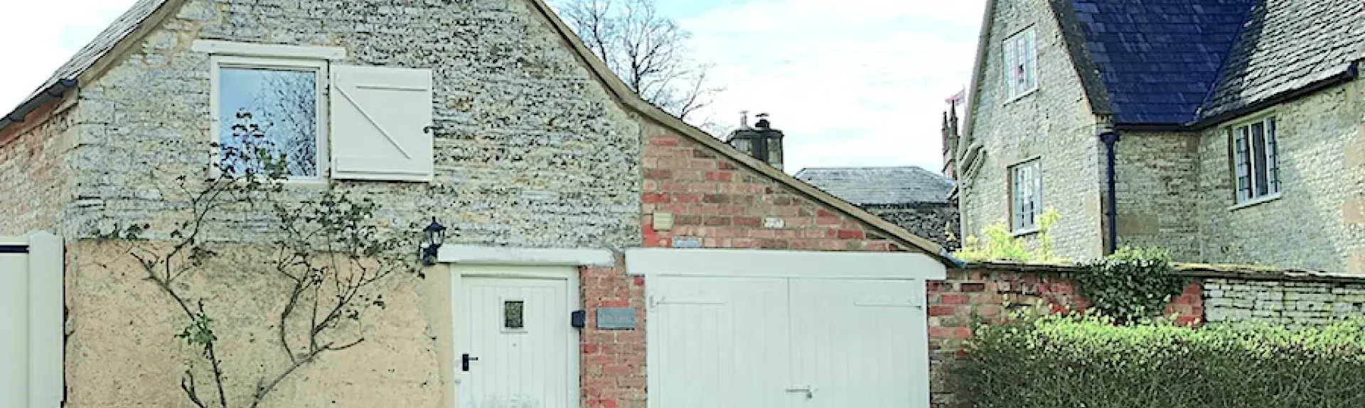 Gable end of an old bothy converted to a holiday cottage with a large lawned garden.