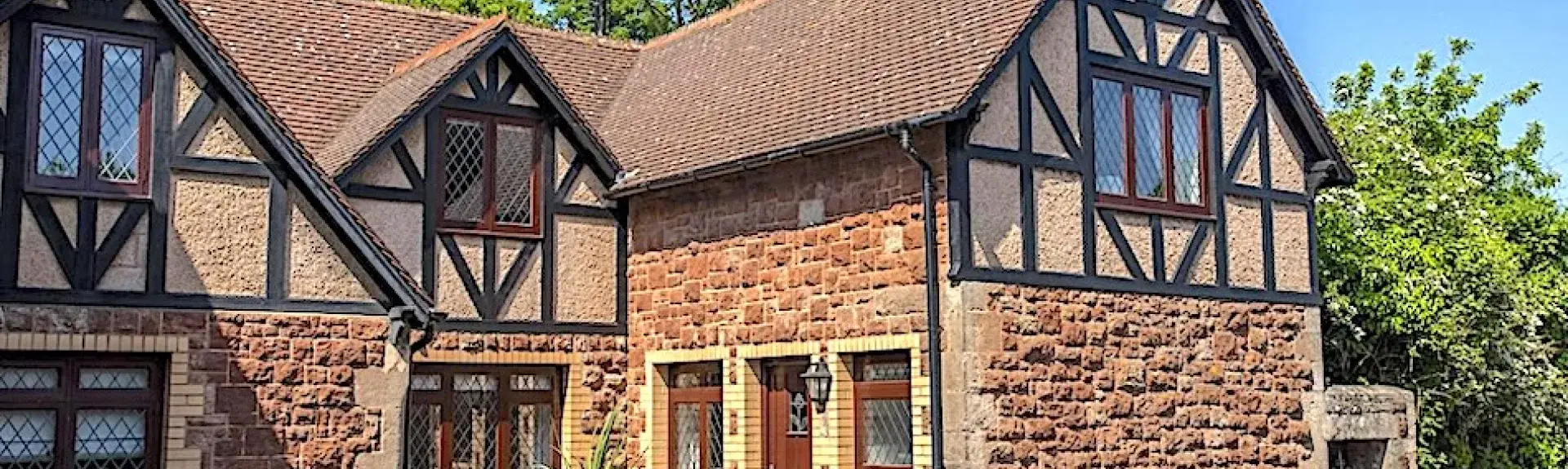 Exterior of a stone-built holiday cottage in Dunster with a secure front garden.