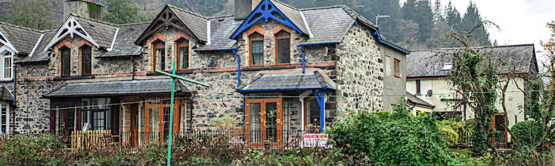 A twin gabled house with bay windows overlooks a railway line and fields.