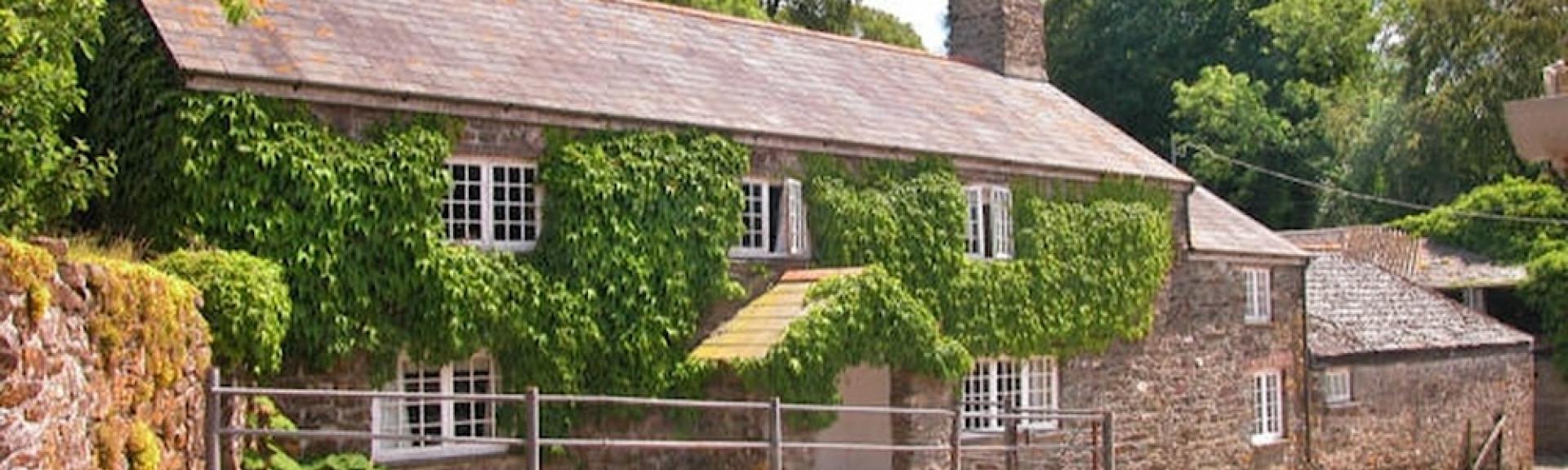 Exterior of a bushy ivy-clad Dartmoor farmhouse.