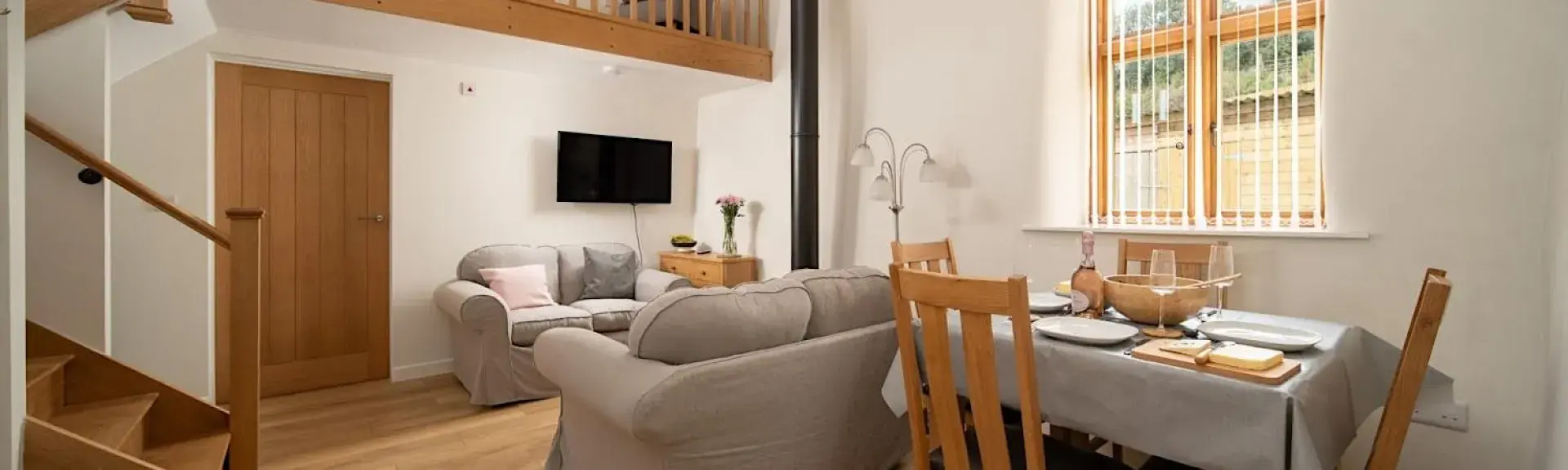 An open plan lounge with sofas, TV and a dining table and chairs.