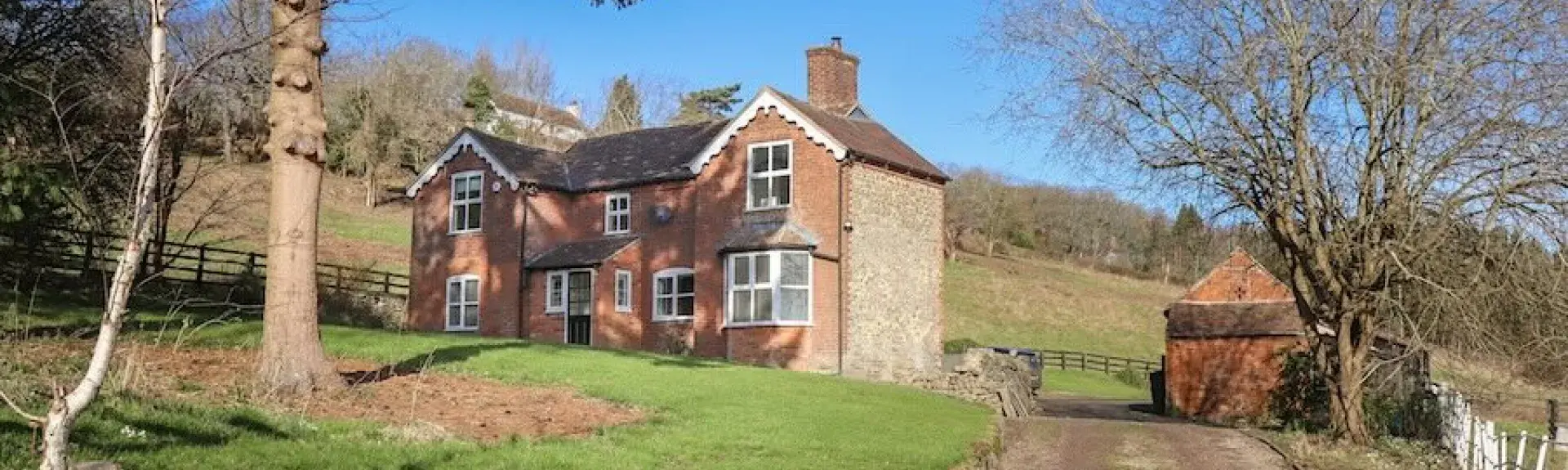 A track leads to a twin-gabled house with a monkey puzzle tree in the foreground.